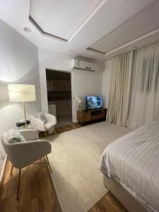 ein Schlafzimmer mit einem Bett, einem Stuhl und einem TV in der Unterkunft استوديو هادي بموقع مميز in Riad