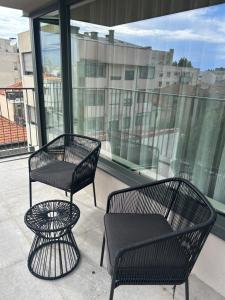 2 sillas negras y una mesa en el balcón en Leça Apartments, en Leça da Palmeira
