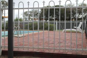 une clôture en face d'une piscine avec des balançoires dans l'établissement Highway One Motel, à Port Augusta