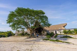 een man die voor een huis staat met een boom bij Hotel Piedra Mulata - Adults Only in Doradal