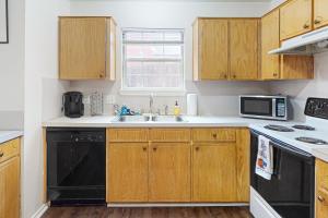 a kitchen with wooden cabinets and a black dishwasher at Brickside Beauty in Killeen