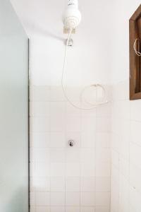 y baño con ducha y pared de azulejos blancos. en Ilhabela Chalés, en Ilhabela