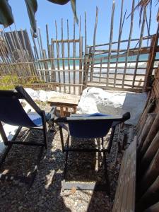 zwei Stühle und ein Tisch vor einem Zaun in der Unterkunft Mancora Apartments in Máncora