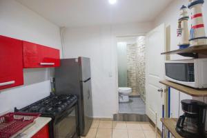 une petite cuisine avec des placards rouges et un four micro-ondes dans l'établissement 3 Departamentos con 5 Habitaciones en Zona Romántica, à Puerto Vallarta