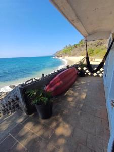 a red boat sitting on a patio next to the beach at Loft Playa Los Venados #2 in Lo de Marcos