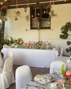 una sala da pranzo con tavolo, sedie bianche e fiori di Hotel Fundo Las Tortolas a Limache