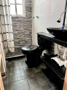 a bathroom with a black toilet and a sink at Hidden house in Mexico City