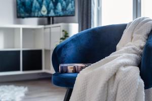 uma cadeira azul debaixo de um cobertor com um livro. em DREAMY modern 3ppl apartment 13 min to Old Town and Central Station em Varsóvia