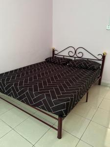 a bed with a black and white comforter on it at Amir homestay kg pandan in Kuantan