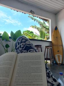 an open book sitting on a chair with a surfboard at LahSelva Pousada Hostel in Itacaré
