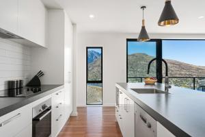 a kitchen with white cabinets and a large window at Style & Tranquillity - 4 Bedroom House in Queenstown