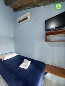 a room with a bed with a tv and a desk at Pousada Arthemis in Garopaba