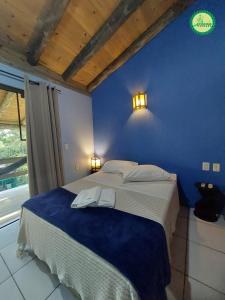a blue bedroom with a bed with two towels on it at Pousada Arthemis in Garopaba