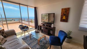 a living room with a couch and chairs and a television at Hermoso Departamento Iquique in Iquique