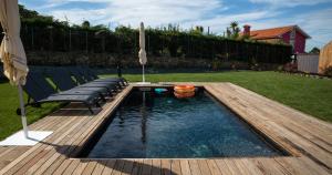 a pool with a deck and chairs in a backyard at Doniños Nature in A Coruña
