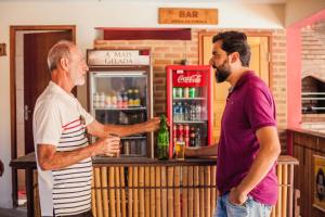 two men standing at a bar with a drink at Pousada O Meu Canto in Santa Rita de Jacutinga