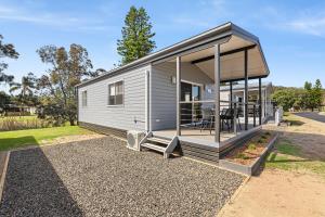 a tiny house with a large window and a patio at Barlings Beach Holiday Park in Tomakin