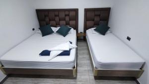 2 camas con sábanas blancas y almohadas azules en una habitación en Hostel Boutique Nido de Loros en Medellín