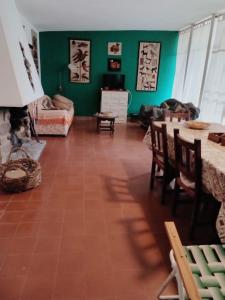 sala de estar con paredes verdes, mesa y sillas en La casita de Calamuchita en Los Reartes