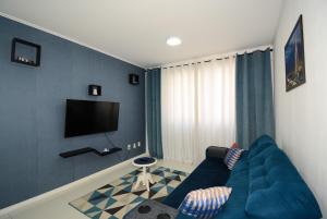 ein Wohnzimmer mit einem blauen Sofa und einem TV in der Unterkunft ótima localizacao e perto de tudo in São José