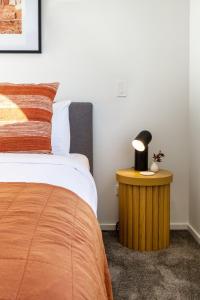 ein Schlafzimmer mit einem Bett und einem Tisch mit einer Lampe in der Unterkunft Garden City Getaway 2 bed with sofa bed 1 bath in Christchurch