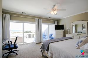 泰碧島的住宿－Beachfront Oasis At Tybee Island，一间卧室配有一张床、一张书桌和一个窗户。