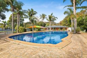 uma piscina com palmeiras e um gazebo em Barlings Beach Holiday Park em Tomakin
