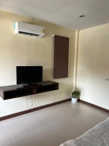 a living room with a television and a air conditioner on the wall at P.F. Poolvilla in Ban Ko Khwan