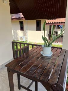 un tavolo in legno con una pianta in vaso su un portico di P.F. Poolvilla a Ban Ko Khwan