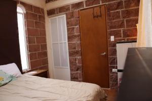 een kamer met een bed en een bakstenen muur bij KOLSA in Santa María Tonantzintla