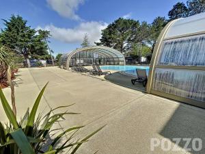 une piscine à côté d'un immeuble avec piscine dans l'établissement Chalet à Jullouville - 6 couchages, piscine chauffée, proche plage et commerces - FR-1-361-521, à Jullouville