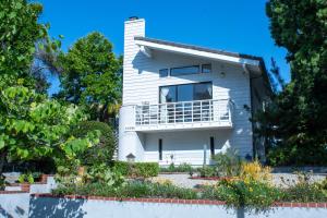 a white house with a balcony and trees at Large Luxury Studio with View in Santa Monica in Santa Monica