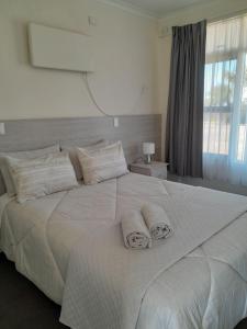 a large white bed with two towels on it at Norfolk Pines Motel in Merimbula