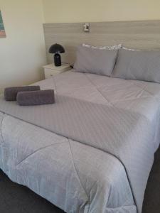 uma cama grande com lençóis brancos e almofadas em Norfolk Pines Motel em Merimbula