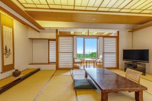 a living room with a table and a television at KAMENOI HOTEL Aomori Makado in Noheji