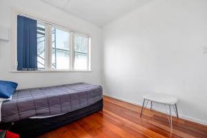 een slaapkamer met een bed, een kruk en een raam bij Lakeview Small Studio in Rotorua