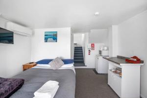 a small bedroom with a bed and a kitchen at Lakeview Small Studio in Rotorua