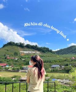 een vrouw met een masker op die naar een berg kijkt bij Cao nguyên in Mộc Châu
