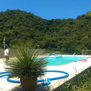 a swimming pool with a potted plant next to it at Refúgio dos Moreiras in Monteiro Lobato