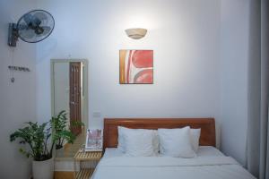a bedroom with a bed with white sheets and a fan at Hanoi All Nations Homestay in Hanoi