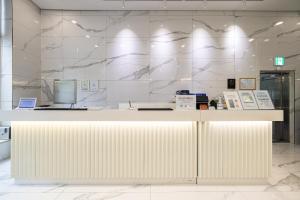 a lobby with a white counter and a marble wall at GL City Hotel Incheon Airport in Incheon