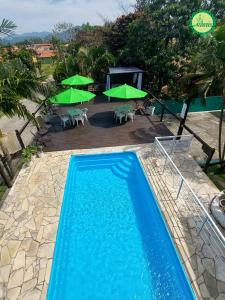a swimming pool with tables and green umbrellas at Pousada Arthemis in Garopaba
