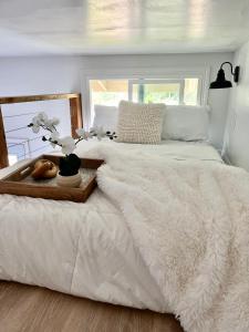 a white bed with a wooden tray with flowers on it at Hale ‘Aina (Country Cottage) in Keaau