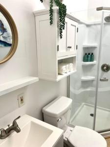 a white bathroom with a toilet and a sink at Hale ‘Aina (Country Cottage) in Keaau