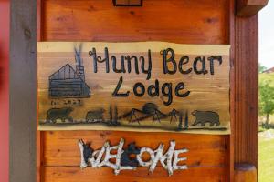um sinal numa parede de madeira com as palavras alojamento de ursos polegares em Huny Bear Lodge em Pigeon Forge