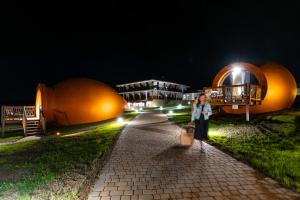 Hotel Qvevrebi في تيلافي: a woman walking down a path in front of dops at night