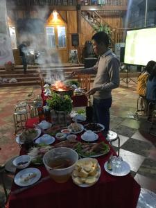 un hombre parado frente a una mesa con comida en Cao nguyên, en Mộc Châu