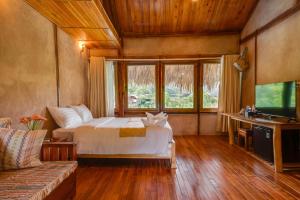 sypialnia z łóżkiem, kanapą i telewizorem w obiekcie Mai Chau Onsen Retreat w mieście Mai Châu