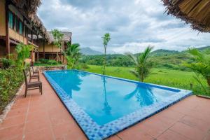 uma piscina num resort com vista para um campo em Mai Chau Onsen Retreat em Mai Châu