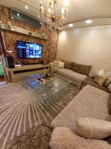 Big, stylish and modern apartment with hot tub في طنجة: غرفة معيشة مع أريكة وطاولة زجاجية
